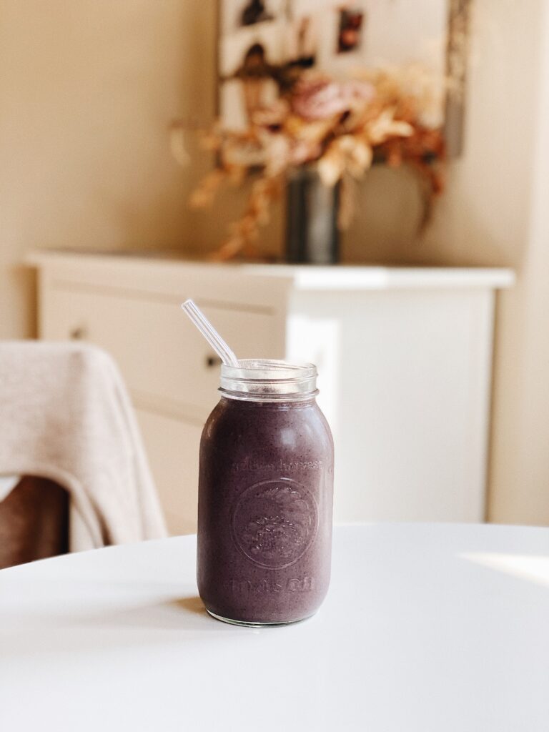 loaded smoothie in large mason jar with glass straw